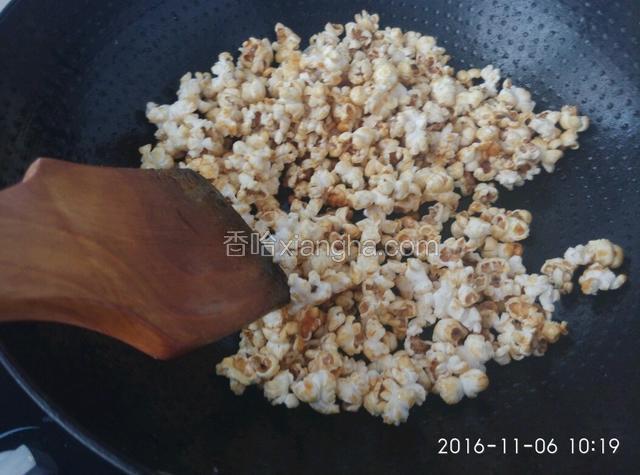等爆裂的声音不再那么密集，变成零星的时候，揭开锅盖。再继续翻炒，让糖和奶粉能够均匀的粘在爆裂的玉米粒上。