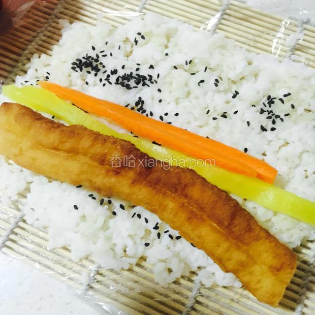 蒸好的糯米铺在铺有保鲜膜的竹帘上
撒上黑芝麻，萝卜条、胡萝卜、油条