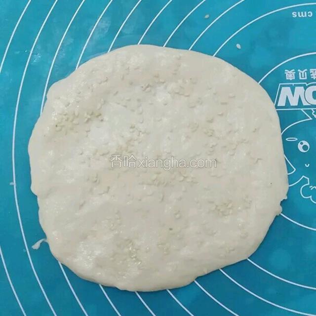 
取一份小面团手上沾点油把它压成圆面饼，然后压上一点白芝麻会很香。
