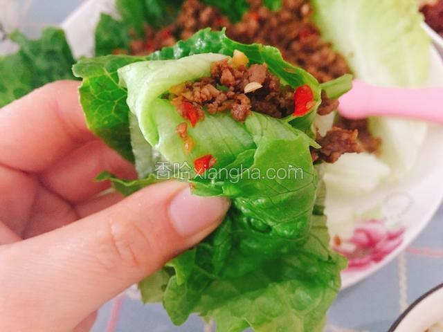 拿上一片菜叶子包着肉末，吃起来特别香。