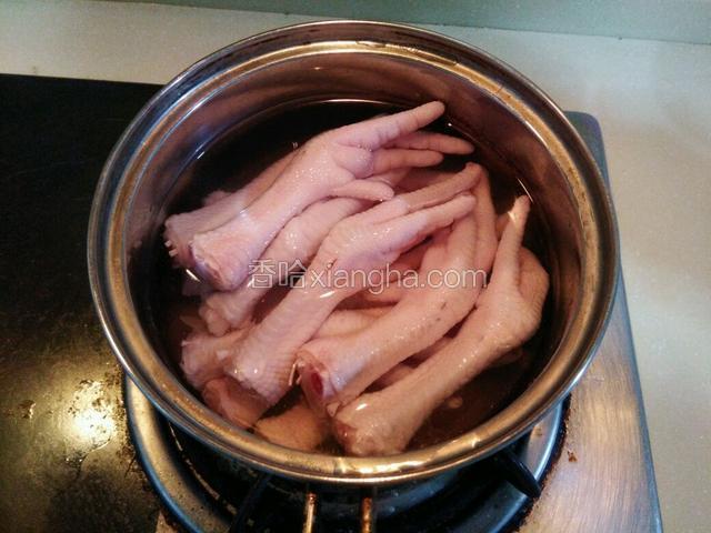 锅加水将鸡爪倒入，加一勺料酒煮开焯水
