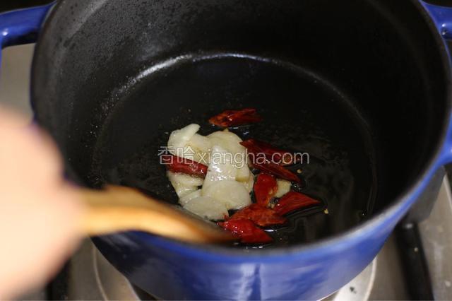 砂锅中加油（这里用了铸铁汤锅），用中火加热，放入蒜片、干红辣椒煸出香味，捞出另放备用。