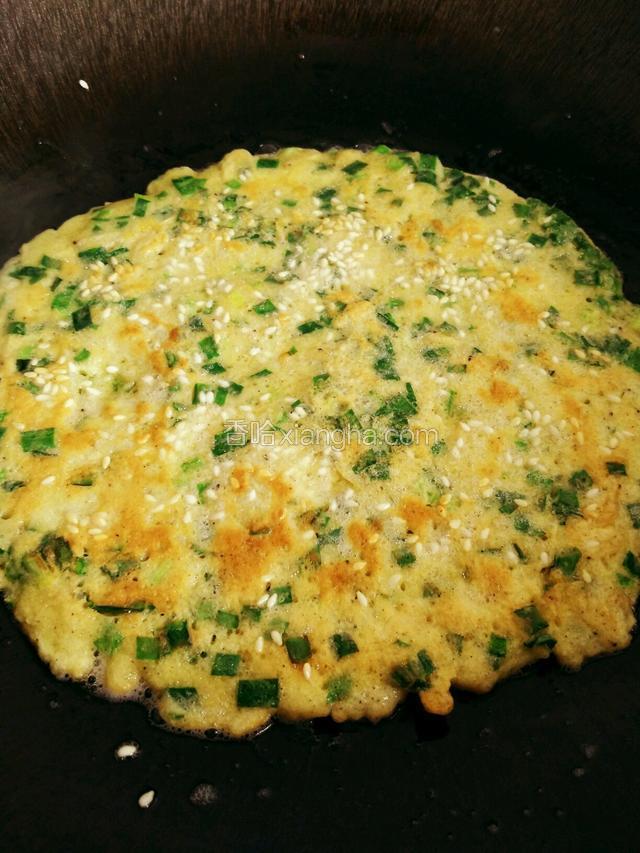 面糊凝固前撒上白芝麻，
观察饼四周发黄，微微翘起即可翻面，小火两面煎黄