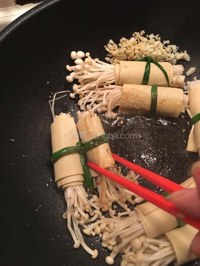 大概煎一分钟左右，用筷子将金针菇豆皮卷翻面，煎另一面
