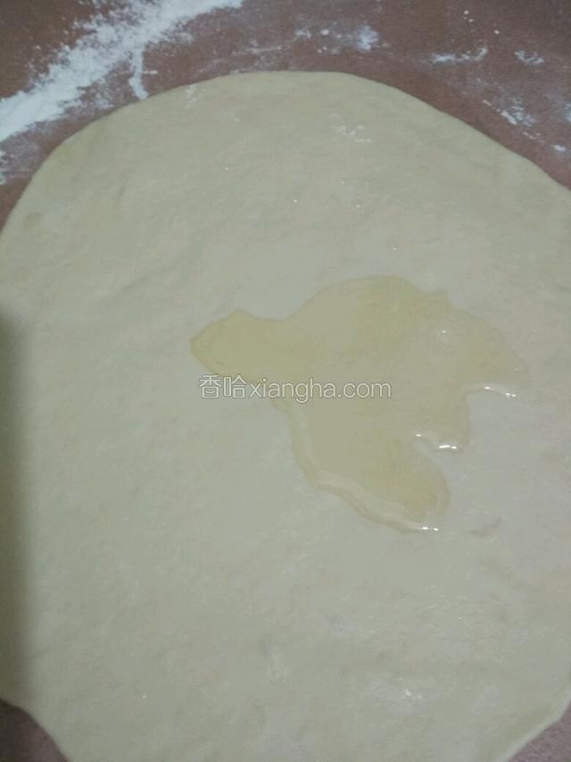 取一块面团用擀面杖擀成薄片，勺上适量的食用油