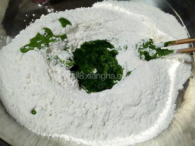 和面盆放入一半的面粉用菠菜汁和面。
