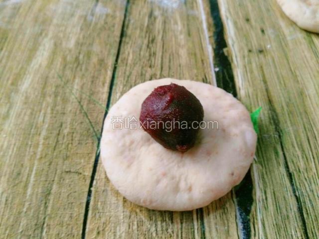 取一面剂放手上按成饼胚状，将豆沙馅放面皮中间，豆沙馅的量每个约10多克。
