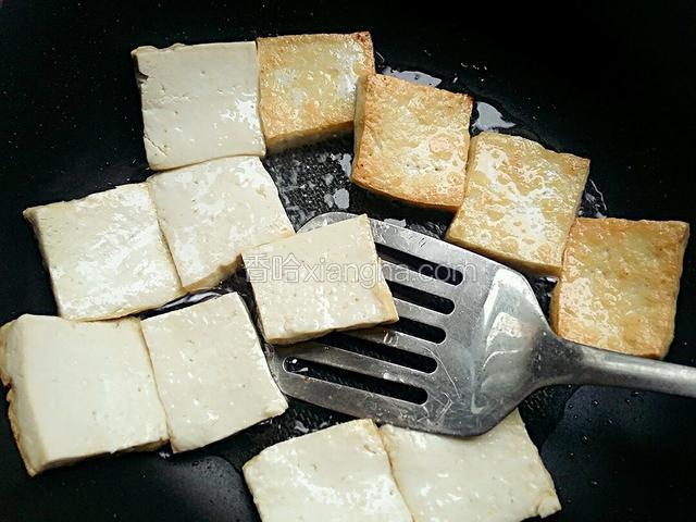 待贴锅的一面豆腐煎黄时，迅速用锅铲翻面，继续小火把另一面煎黄