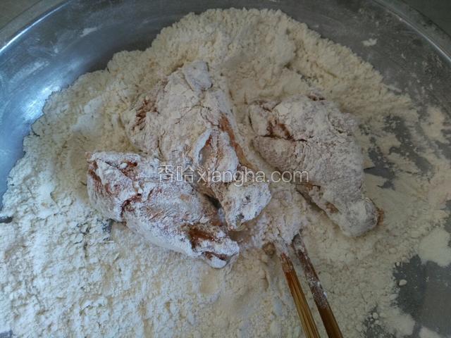 在拿一个大点的盆倒入多一点的裹粉，把腌制好的鸡翅根放入裹粉中，一次放三个就可以，方便裹粉。