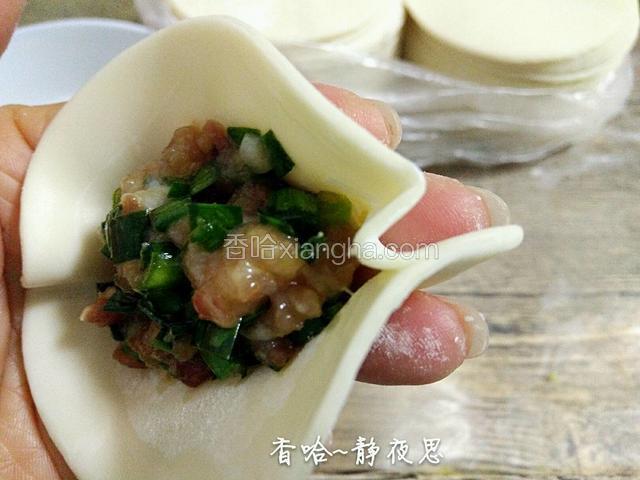 左手食指推动最前面的一片饺皮，推出褶皱，右手食指和大拇指把褶皱捏紧