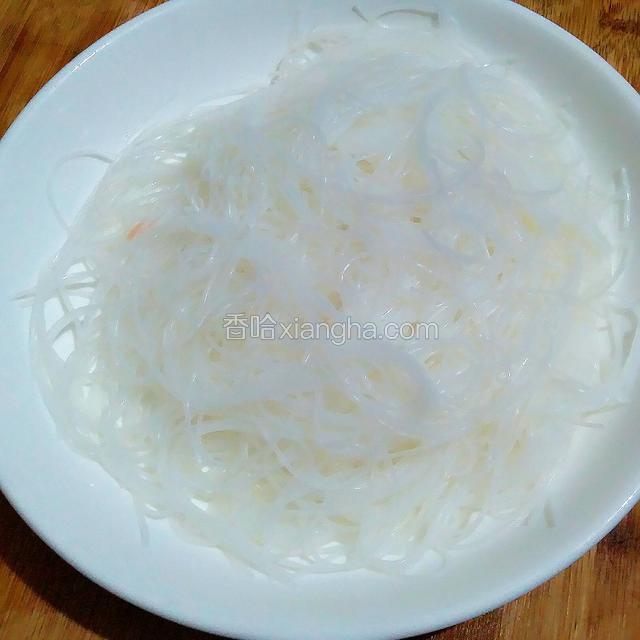把泡发好的粉丝沥水后，稍稍煎短，铺在一深口盘内。这会可以把锅里加水烧上