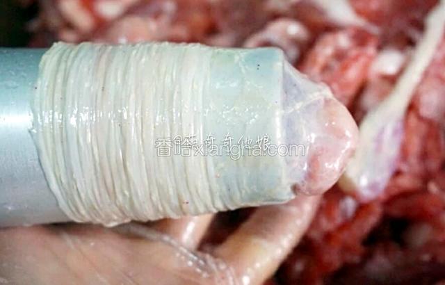 以上四种你们自行选择，个人更偏向于第二种，洞口大灌起来相对轻松很多，操作顺手了没多久就能灌好。
不过不论选用哪种手工工具，首先把肠衣一头套上，然后先灌一点肉进去捏到尾部，然后在肠尾部打个结，再把肠套在管子上，如图，就可以灌肉了。
先灌一点肉进去是因为肉上的油脂会润滑肠内部，使灌肉更顺滑轻松。
手工灌肠会有空气进入肠内，用牙签戳破就行了。