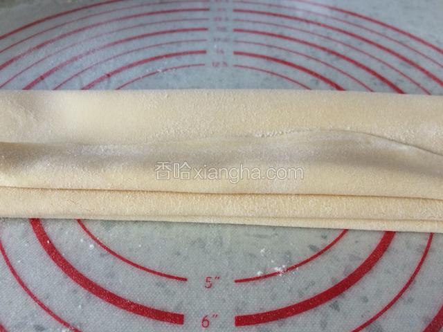 面前撒一层薄面，叠成八厘米左右宽度，如图，这个宽度比较好切