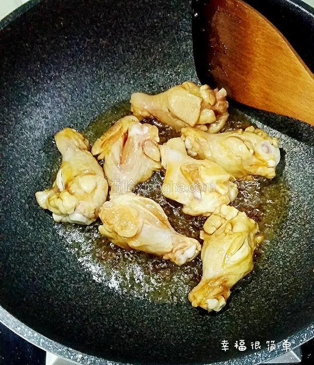 冰糖溶化后，倒入鸡腿开始染糖色。这个过程一定要开小火，不停的用木铲翻炒鸡腿。