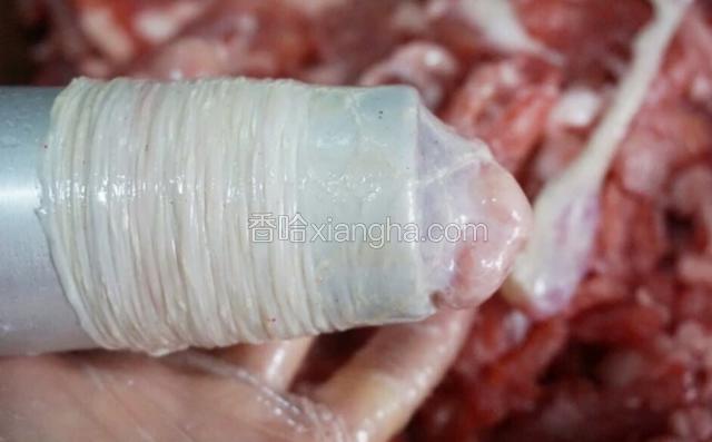 以上四种你们自行选择，个人更偏向于第二种，洞口大灌起来相对轻松很多，操作顺手了没多久就能灌好。
不过不论选用哪种手工工具，首先把肠衣一头套上，然后先灌一点肉进去捏到尾部，然后在肠尾部打个结，再把肠套在管子上，如图，就可以灌肉了。图是借用茹的。
先灌一点肉进去是因为肉上的油脂会润滑肠内部，使灌肉更顺滑轻松。
手工灌肠会有空气进入肠内，用牙签戳破就行了。