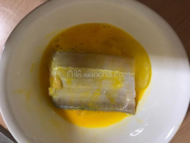 将带鱼段放入蛋液中，两面都蘸满蛋液。