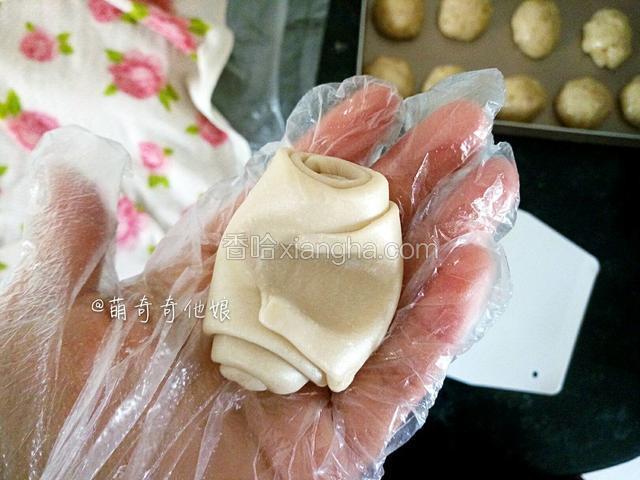 取一松弛好的酥皮，从中间位置按扁，如图。
包馅儿的时候建议戴一次性手套操作，可以避免擀面丈擀的时候擀破或粘破。