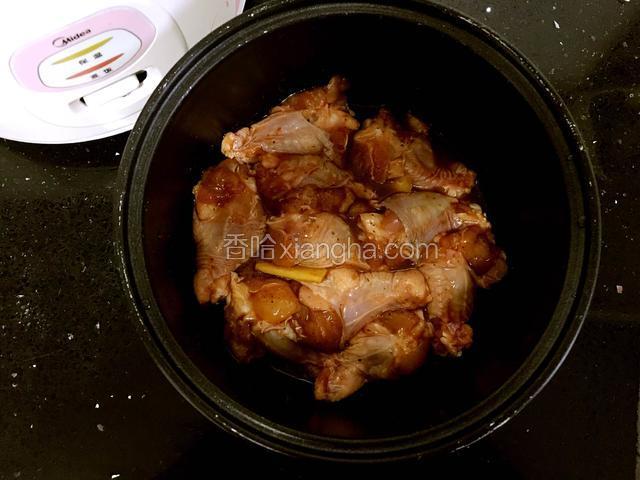 把腌制好的翅根放到电饭煲内胆中。腌出的汁也一起放入。把内胆放入电饭煲中，按下煮饭键。