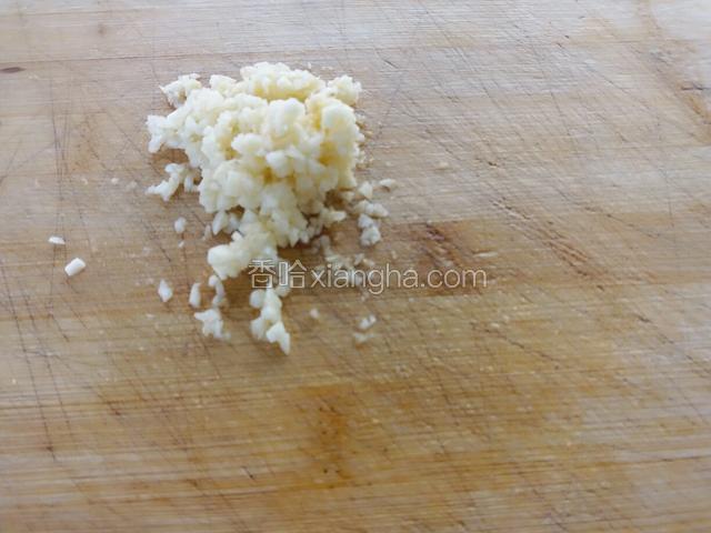 蒜瓣在熟菜板上用刀剁成蒜末