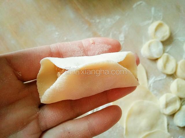 用右手拿起面皮中间捏紧（如图）。