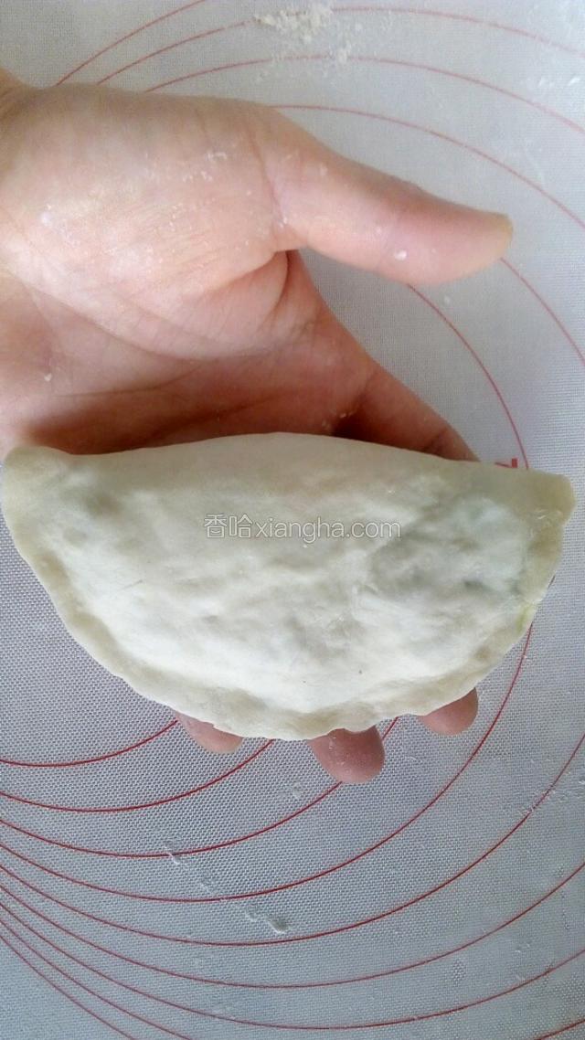 将饺子皮的两侧合到一起，使其包住菜馅，将重合的边缘捏严捏紧。
