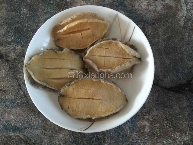 鲍鱼去壳去内脏，用牙刷将四周黑色的物质尽量洗刷干净，切花刀备用。