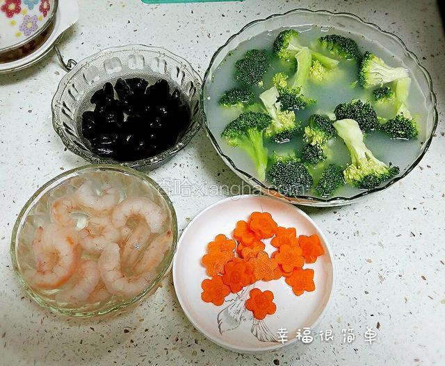 准备两碗淘米水，西兰花整朵地漫泡在淘米水中半小时后，掰开小块继续泡到另一碗淘米水中。干木耳用开水泡发，胡萝卜用模具压成小花。虾仁开背去虾线，食材全部准备好。