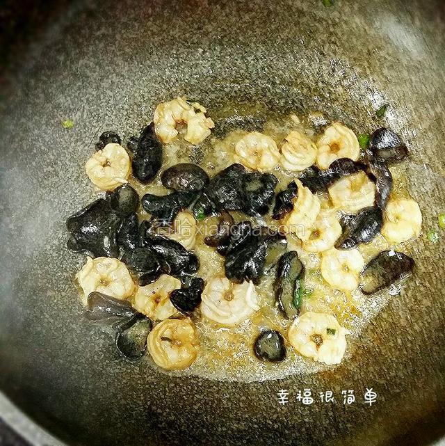 锅中倒入适量的清油，放入少量的葱花，先将虾仁和黑木耳倒入煸炒。