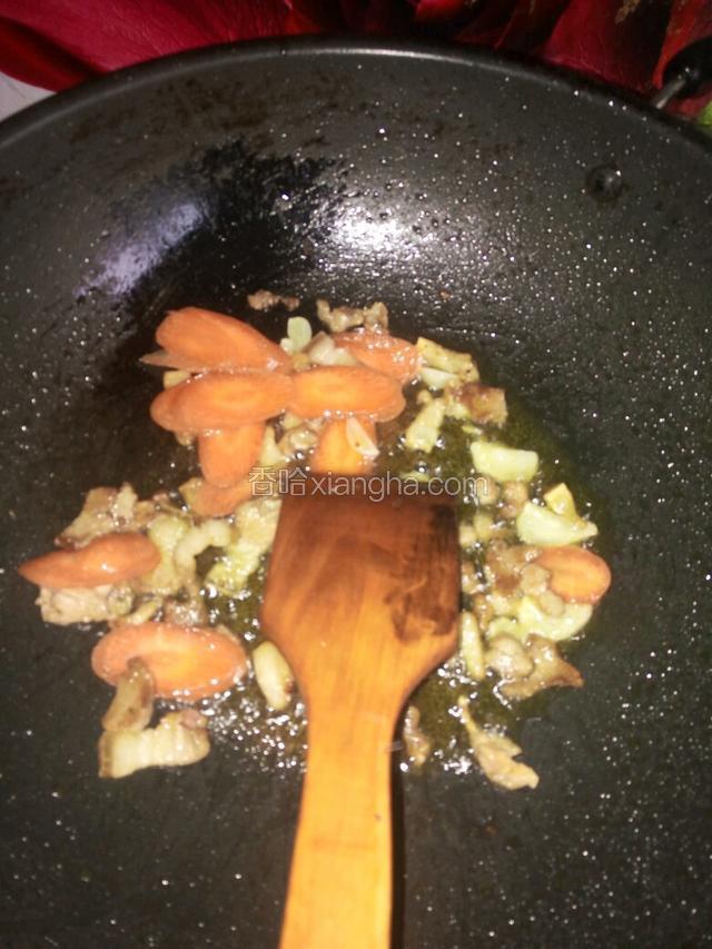 继续用剩的油炒肉加入蒜，炒一分钟后放入胡萝卜片，到胡萝卜软熟后继续放入木耳，绿辣椒。