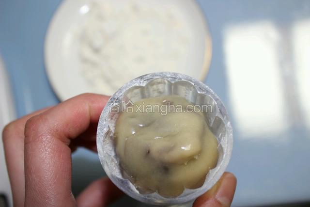包好的月饼表皮面也轻轻的抹一层干面粉。
把月饼球放入模型中压平。
