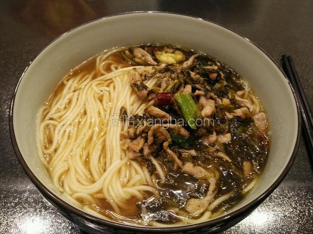 将炒好的雪菜肉丝盛在面条上面。