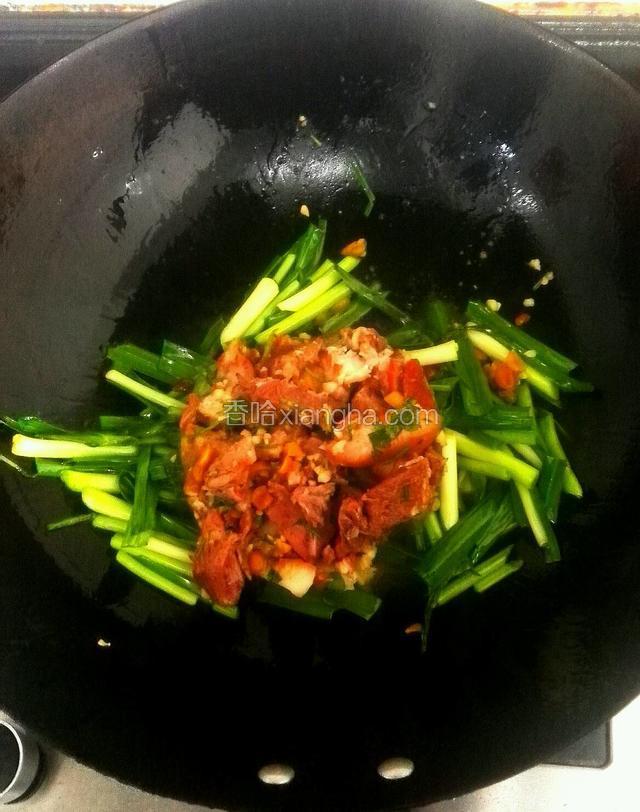 把猪头肉倒入翻炒均匀的大蒜叶内