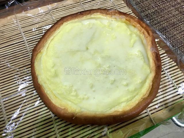 寿司卷帘铺上保鲜膜，将冷却后的蛋糕放上去，抹上一层炼乳