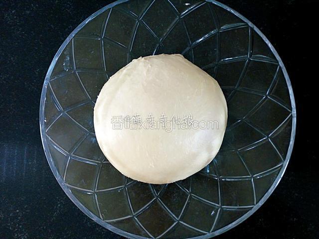 滚圆盖保鲜膜，在温度为28度的环境中进行基础发酵。
面团湿度比较大会粘手，可以借助刮板铲一下边缘使之成光滑圆形。