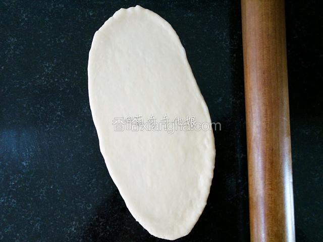 取一松弛好的面团，擀开成椭圆形。
面团比较粘手可以在操作台上撒少许干粉防粘或者滴一滴植物油抹开防粘，方便整形，但不可过多。