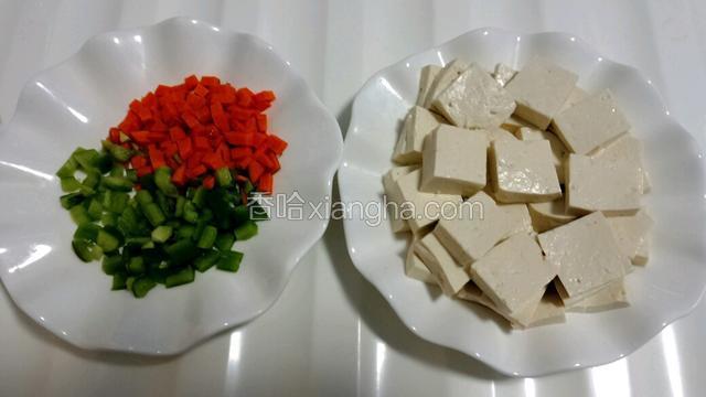 准备食材，把豆腐切均匀小块，胡萝卜切丁，青椒切丁。