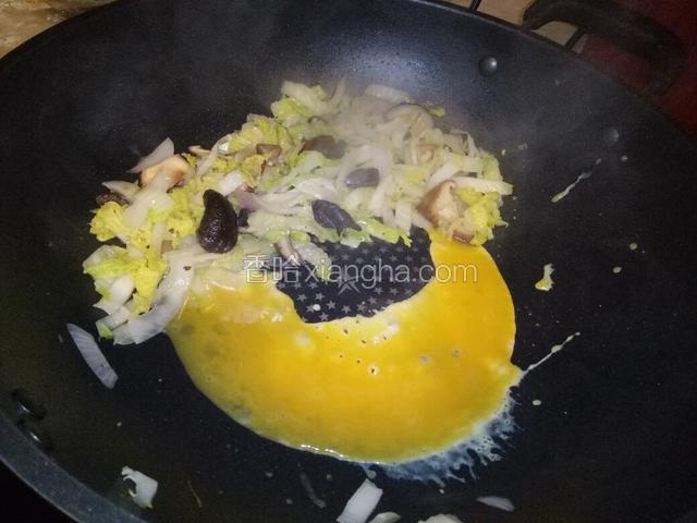 把娃娃菜和冬菇炒至半熟，推往锅的一侧，另一侧倒进鸡蛋。