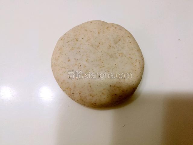 包好的面团收口朝下放置，并用手压扁成为圆饼状。