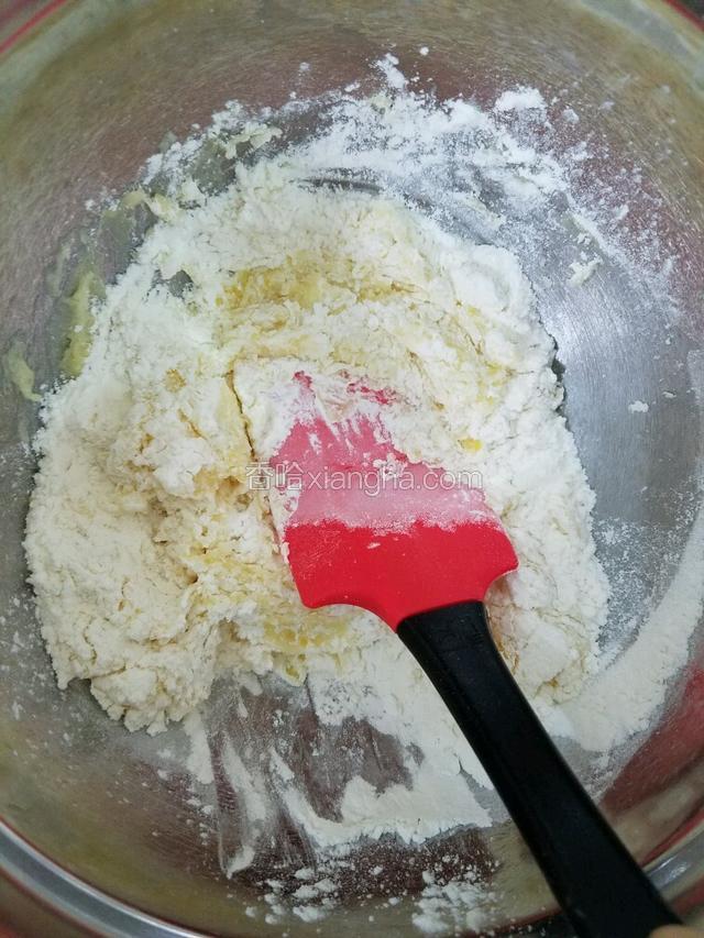 用刮刀以压拌或切拌的手法将面粉和黄油混合均匀。