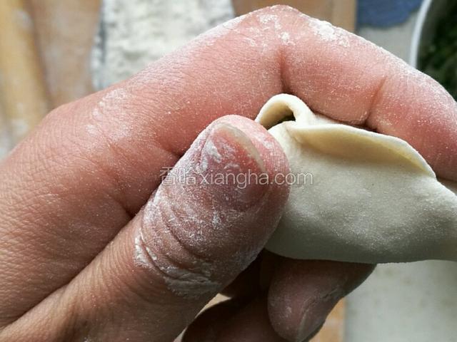 中指托住饺子肚，两手同时用拇指和食指捏紧饺子。