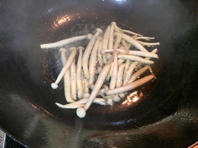 热锅倒油烧热，下入已清洗好的白玉菇翻炒片刻