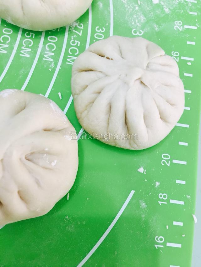 撒点干粉在揉面垫上，依次把包好的肉包放好。