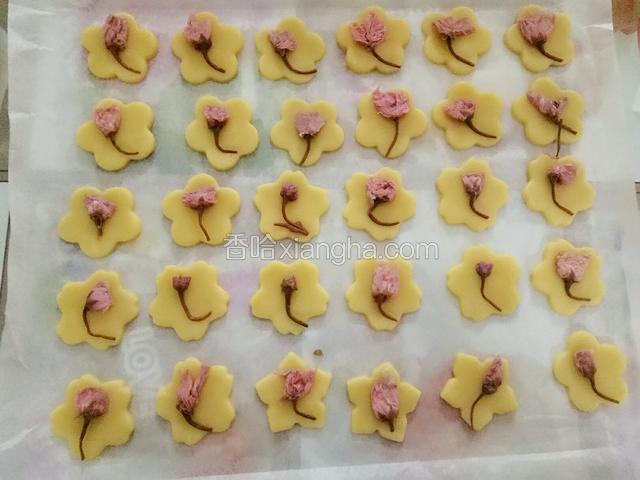 将泡开的樱花挤干水分放在饼干上