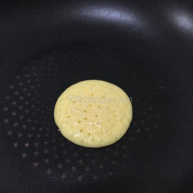 平底锅上火，热锅后用小火，舀一勺蛋糊在中间自然摊开，小火煎烙成小圆饼。
