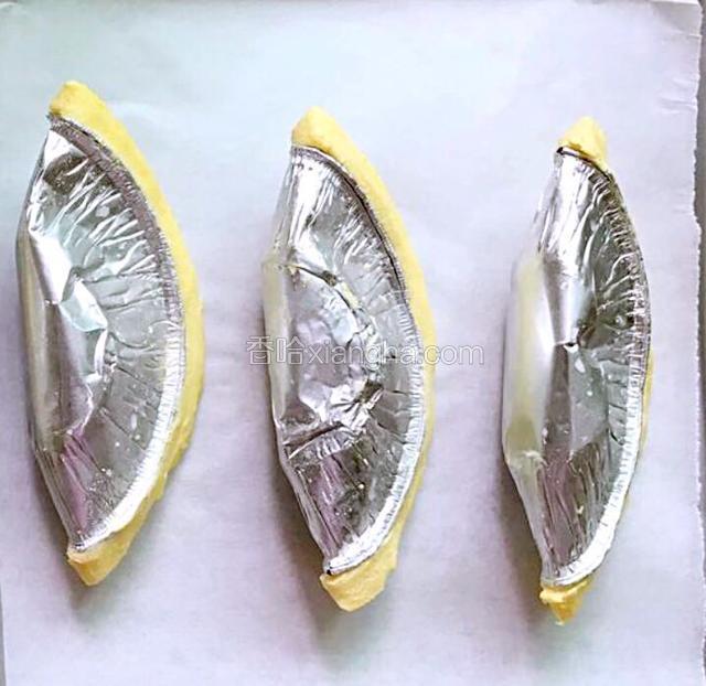将榴莲肉铺在蛋挞皮上，中间放入两小条奶油奶酪，对折，注意不要将口封紧，轻轻对折，容易起酥！