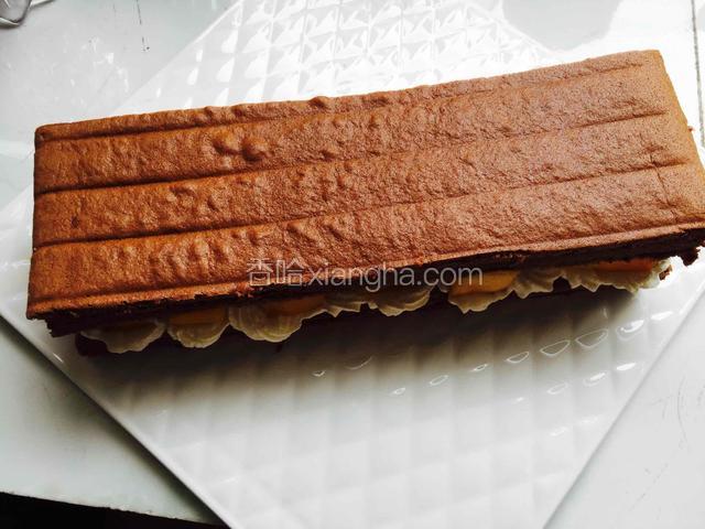 再盖上一片蛋糕片，再挤上奶油，放上芒果。