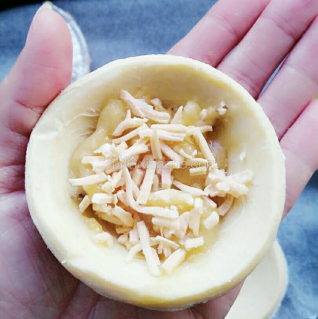 将榴莲肉铺在蛋挞皮上，中间放少许奶酪丝，轻轻对折，不要封口，这样容易起酥！