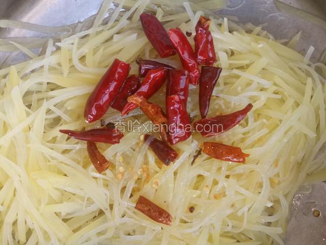 把辣椒油同辣椒一同倒入土豆丝中