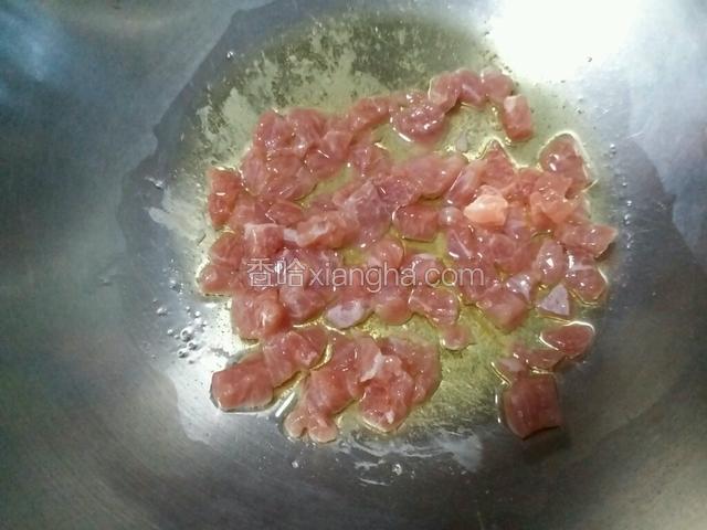 锅内放入适量食用油，烧热后放入猪肉丁，翻炒至肉丁变色断生。