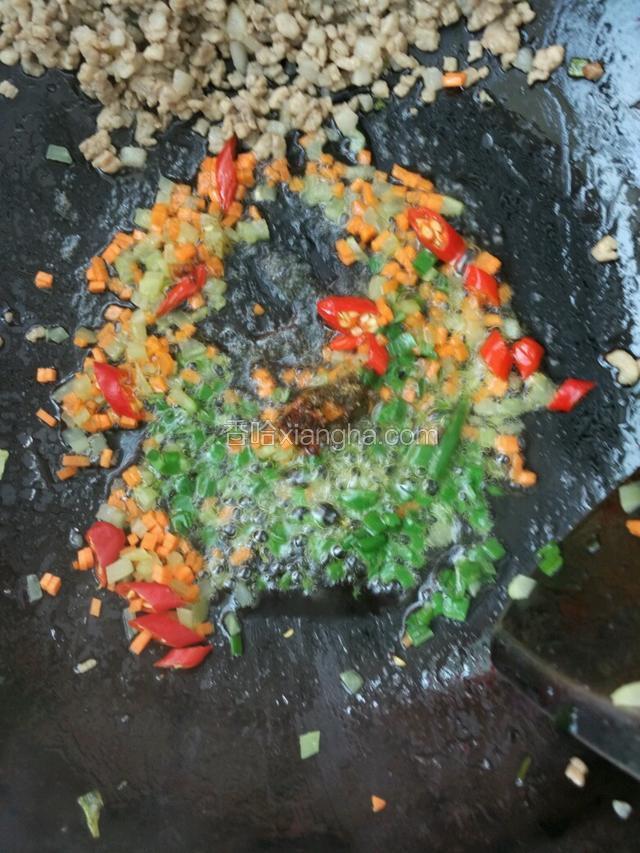 把肉沫拨到锅边，倒入胡萝卜莴笋丁、小米椒和葱沫翻炒，期间放入少量花椒粉、大料粉、老抽和蚝油